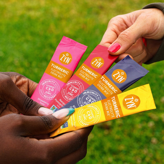 One of each ZYN Turmeric Electrolyte Sachets in a persons hand.